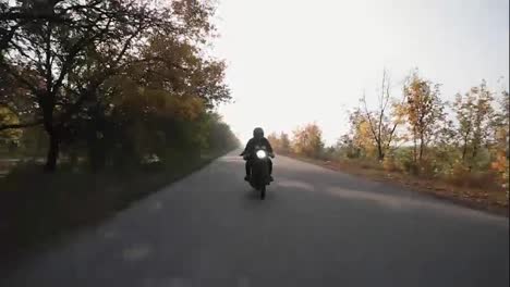 Vorderansicht-Eines-Mannes-Mit-Schwarzem-Helm-Und-Lederjacke,-Der-Auf-Einer-Landstraße-Motorrad-Fährt