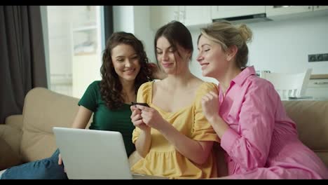 Three-women-in-colorful-dresses-preparing-to-spend-money-online-with-card