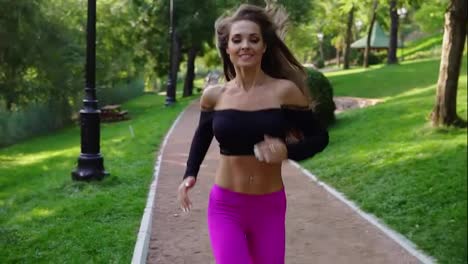 Young-woman-in-sporty-bra-running-in-the-sunny-city-park-exercising-outdoors.-Steadicam-stabilized-shot,-Slow-Motion.-Morning