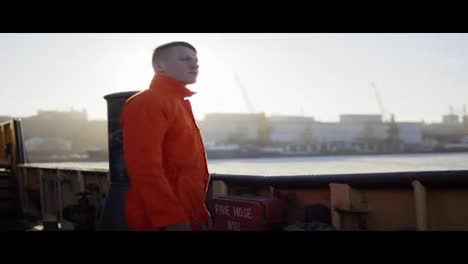 Hafenarbeiter-In-Orangefarbener-Uniform,-Der-Am-Bord-Des-Schiffes-Steht.-Linseneffekt.-Zeitlupe