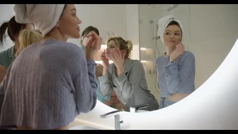 Three-young-women-laughing-and-talking-in-bathroom