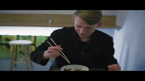 Close-Up-view-of-a-man-trying-to-eat-noodles-using-chopsticks.-Learning-how-to-hold-chopsticks-without-success-and-taking-a-fork