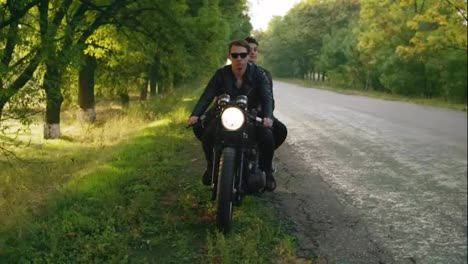 Handsome-man-in-sunglasses-with-his-girlfriend-stopping-his-vintage-motorcycle-on-the-road-side