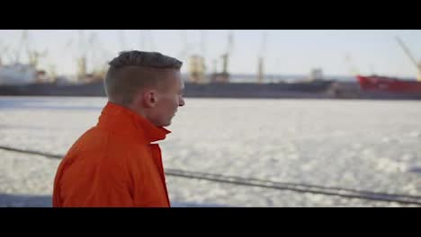 Hafenarbeiter-In-Orangefarbener-Uniform-Geht-Am-Meer-Entlang.-Zeitlupe