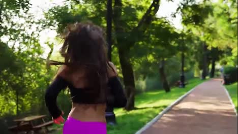 Back-view-of-a-young-woman-in-fuxy-legging-running-in-the-sunny-city-park-exercising-outdoors.-Steadicam-stabilized-shot