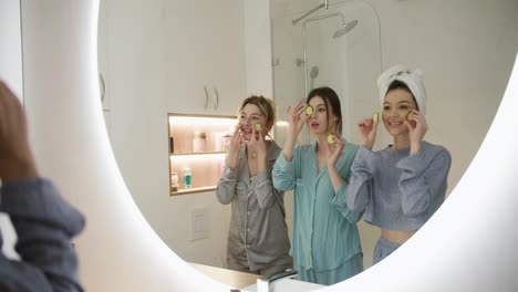 Pajama-party---happy-friends-with-cucumber-mask-having-fun-doing-in-front-mirror