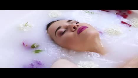 Close-Up-view-of-young-woman's-face-bathing-in-milk-bath-filled-with-flowers-and-getting-up.-Spa-and-skin-care-concept