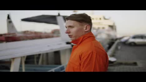 Hafenarbeiter-In-Orangefarbener-Uniform,-Der-Während-Seiner-Pause-Eine-Zigarette-Raucht-Und-Sich-Entspannt.-Zeitlupe