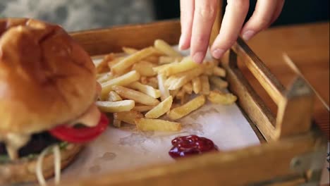 Camera-moves-from-female-hands-taking-french-fries-and-showing-her-smiling-face-while-taking.-Slow-Motion-shot