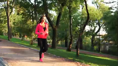 Young-woman-running-in-the-sunny-city-park-exercising-outdoors.-Steadicam-stabilized-shot,-Slow-Motion.-Morning-exercising