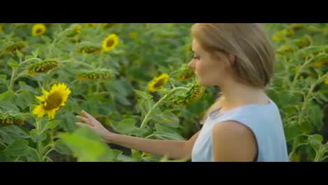 Portrait-of-a-young-woman-in-a-blue-dress-standing-sunflower-field,-enjoying-nature.-Slow-Motion-shot