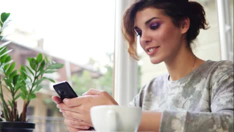 Junge-Attraktive-Frau-Kauft-Online-Mit-Ihrem-Mobiltelefon-Im-Café-Ein-Und-Lächelt.-Frau-Nutzt-App-Auf-Smartphone-Im-Café