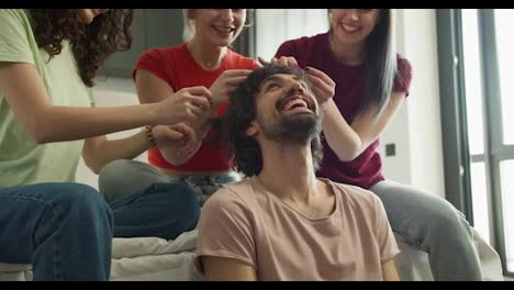 Three-women-having-fun,-creating-new-hairstyle-to-their-male-friend