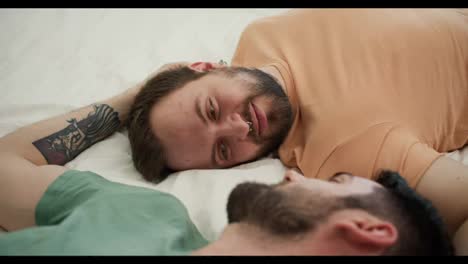 Portrait-of-attractive-bearded-gay-men-couples-lying-on-bed-together,-talking