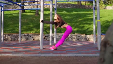 Flexible-young-woman-is-stretching-out-after-long-challenging-running-session-in-green-city-park-at-beautiful-sunny-morning