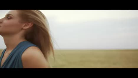 Close-Up-view-of-attractive-young-blond-woman-in-a-blue-dress-walking-through-golden-wheat-field.-Freedom-concept.-Slow-Motion