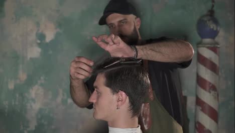 Bearded-barber-putting-hair-pins-to-man's-head-and-brushing-his-hair.-Hair-barrette-on-male-head-in-barber-shot.-Male-hairstyle