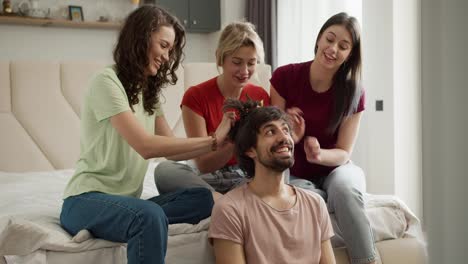 Three-women-having-fun,-creating-new-hairstyle-to-their-male-gay-friend