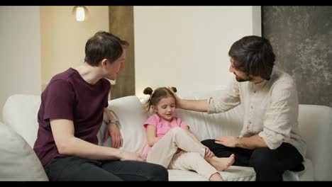 Male-gay-couple-or-uncle-sitting-with-talking-to-the-small-girl-on-the-sofa
