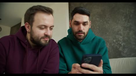 Gay-couple-hold-smartphone-read-good-news-amazed-by-mobile-online-bet-or-news-and-hug