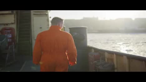 Hafenarbeiter-In-Orangefarbener-Uniform,-Der-Am-Bord-Des-Schiffes-Steht.-Linseneffekt.-Zeitlupe