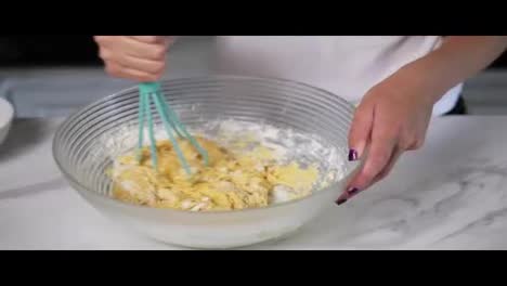 Close-Up-view-of-female-hands-mixing-sticky-dough-in-the-kitchen-using-whisk.-Homemade-food.-Slow-Motion-shot