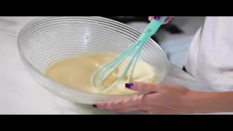 Close-Up-view-of-woman's-hands-mixing-ingredients-to-prepare-dough-in-the-the-bowl-using-whisk.-Home-cooking.-Slow-Motion-shot