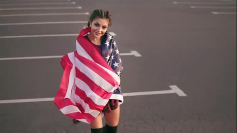 Stolzes-Amerikanisches-Mädchen,-Das-Die-Amerikanische-Flagge-über-Ihre-Schultern-Wickelt-Und-In-Die-Kamera-Schaut.-Zeitlupenaufnahme