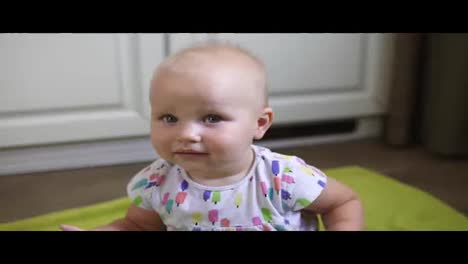 One-year-old-baby-sitting-in-the-kitchen-on-the-floor-and-looking-in-the-camera.-Then-standing-up-and-going-away.-Slow-Motion