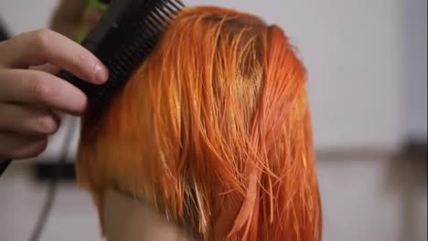 Close-Up-view-of-professional-hairdresser-using-a-hairdryer-after-haircut.-Young-redhead-woman-in-beauty-salon.-Slow-Motion-shot