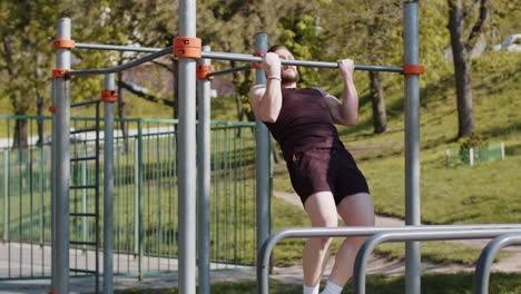 Athletic-lebanese-man-in-sportswear-doing-pull-ups-exercises-on-horizontal-bar,-pumping-up-back