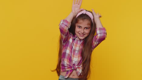 Lovely-funny-comical-child-girl-kid-smiling-friendly-and-doing-bunny-ears-gesture-on-head,-fooling