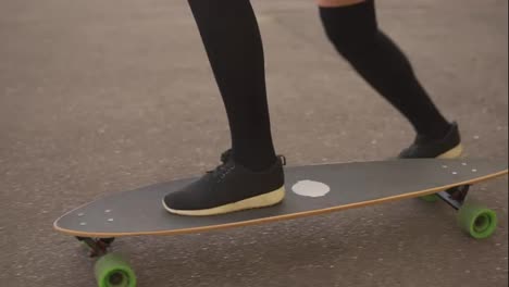 Close-Up-view-of-woman's-legs-in-black-sneakers-skateboarding-on-the-road-in-the-city.-Legs-on-the-skateboard.-Slow-Motion-shot