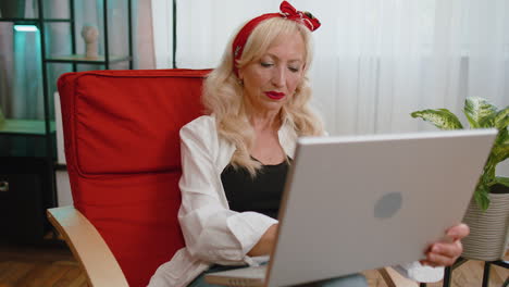 Überglückliche-ältere-Frau,-Die-Am-Laptop-Arbeitet,-Feiert-Erfolg,-Gewinnt-Geld-In-Der-Lotterie-Und-Erhält-Online-Gute-Nachrichten