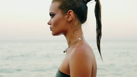 Close-Up-view-of-sexy-woman-with-professional-golden-makeup-and-wet-ponytail-walking-by-the-water-on-the-beach-then-turning-and