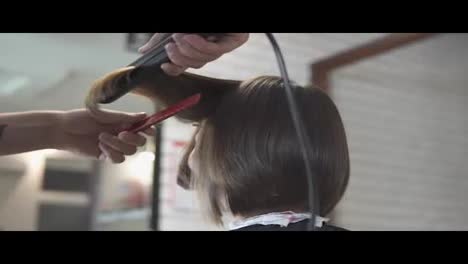 Close-up-shot-of-a-woman-having-her-hair-straightened-in-hair-salon.-shot-in-slow-motion