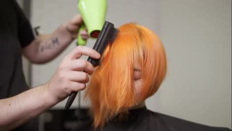 Professional-hairdresser-using-a-hairdryer-after-haircut.-Young-redhead-woman-in-beauty-salon.-Slow-Motion-shot