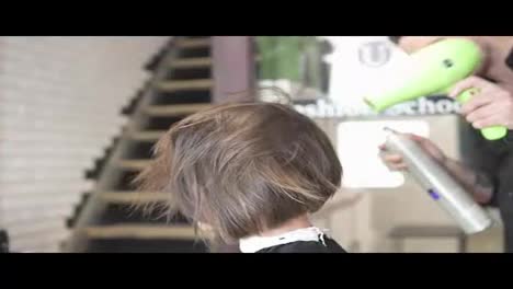 Professional-hairdresser-using-a-hairdryer-after-haircut-and-applying-hair-treatment-spray