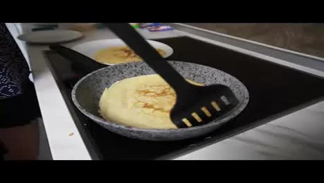 Close-Up-view-of-a-female-hand-with-spatula-taking-a-prepared-pancake-from-the-pan-and-putting-it-to-the-plate.-Homemade-pancakes