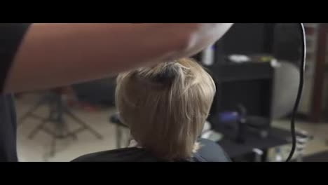 Professional-hairdresser-using-a-hairdryer-after-haircut.-Young-woman-getting-her-hair-dressed-in-hair-salon.-Hair-stylist