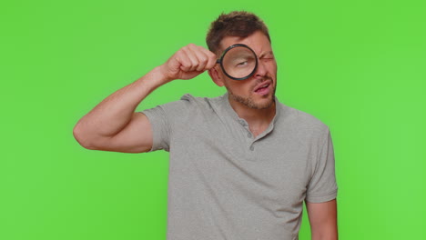 Researcher-scientist-man-holding-magnifying-glass-near-face,-looking-to-camera-with-big-zoomed-eye