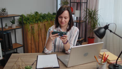 Worried-young-business-woman-enthusiastically-playing-racing-or-shooter-video-games-on-smartphone