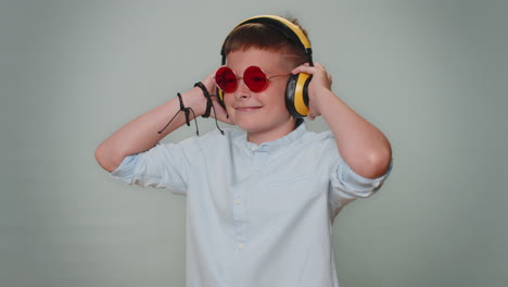 Cheerful-toddler-boy-listening-music-via-headphones-and-dancing-disco-fooling-around-having-fun