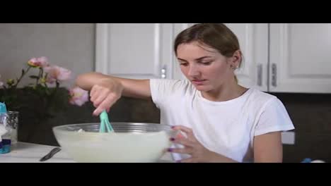 Young-woman-prepares-dough-mixing-ingredients-in-the-the-bowl-using-whisk-in-the-kitchen.-Homemade-food.-Slow-Motion-shot
