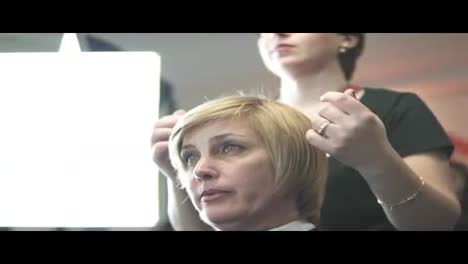 Professional-hairdresser-using-a-hair-treatment-after-haircut.-Young-woman-in-beauty-salon.-Hair-stylist-applying-oil-for-hair