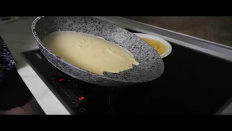 Close-up-view-of-female-hands-pouring-pancake-Mixed-in-a-frying-pan-and-spreading-it-around.-Homemade-food.-Slow-Motion-shot