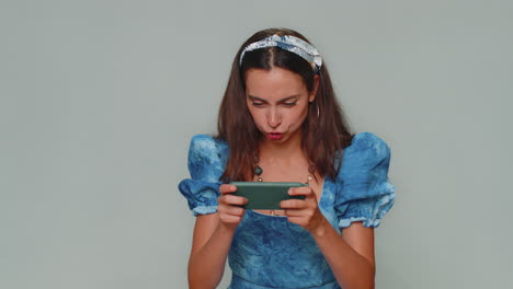 Worried-funny-young-woman-enthusiastically-playing-racing-or-shooter-video-games-on-smartphone