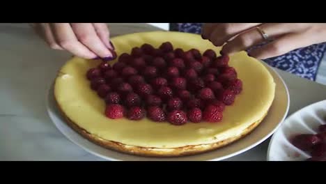 Top-view-of-the-cake-decorated-with-raspberries.-Woman-is-adoring-and-decorating-the-top-of-the-cake-with-raspberries-in-the