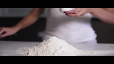 Female-hands-break-the-egg-into-flour-on-the-kitchen-table.-Slow-Motion-shot
