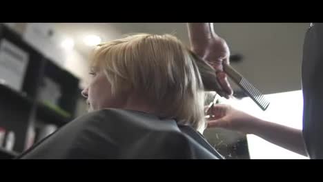 Young-woman-getting-her-hair-dressed-in-hair-salon.-Close-Up-view-of-a-hairdresser's-hands-cutting-hair-with-scissors.-shot-in